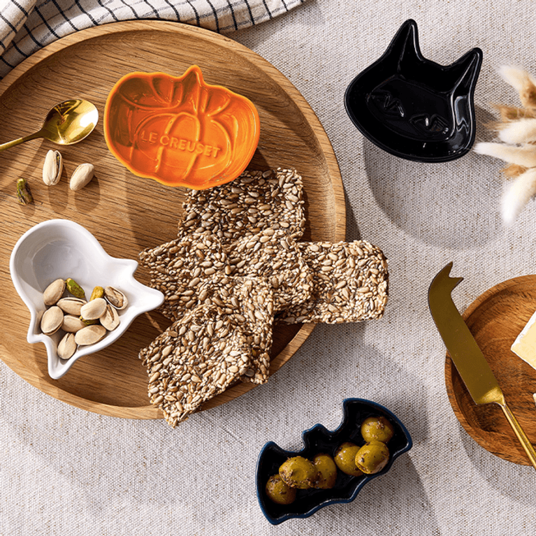 a set of four halloween mini dishes from Le Creuset, with an orange pumpkin; a black cat; a navy bat and a white ghost