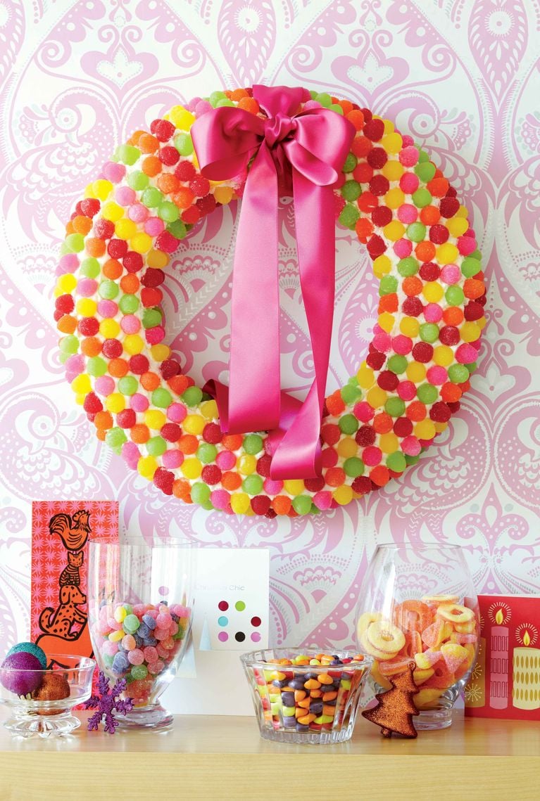 Finished DIY Christmas wreath crafted from a Styrofoam form decorated entirely with royal icing and bulk gumdrops, with a pink ribbon for hanging.