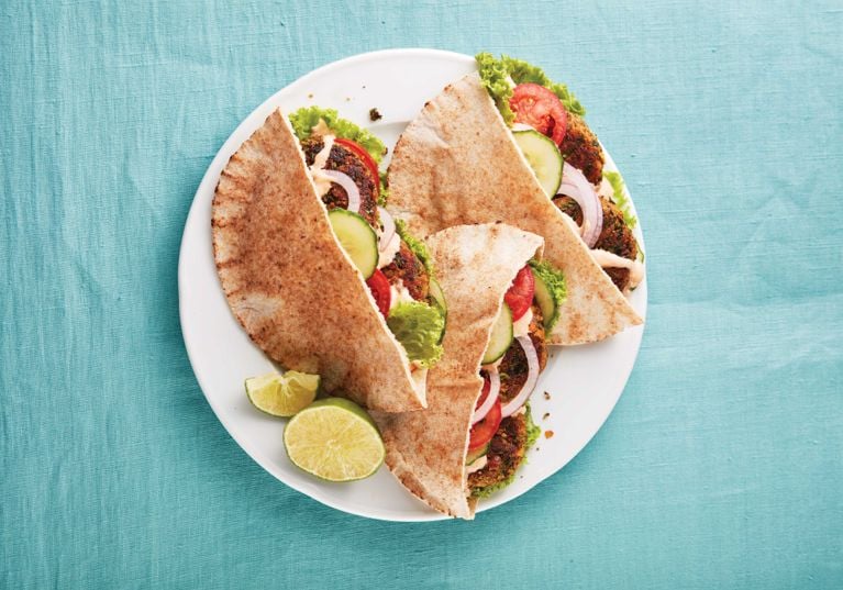 Lentil Cakes With Harissa Yogurt in a pita next to slice of lime on a white plate