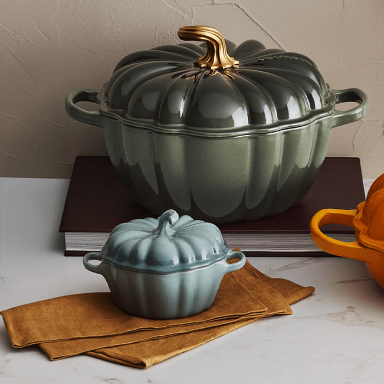 A mini pumpkin cocotte from Le Creuset in sea salt (blue) next to a larger pumpkin dutch oven