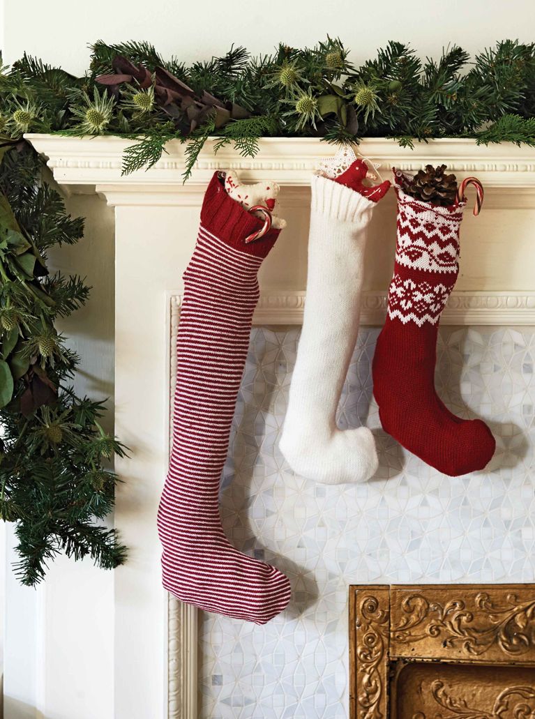 Three Christmas stockings hung from a holiday mantel; all are red and white and made from old sweaters for a post on a craft to make stockings out of old sweaters