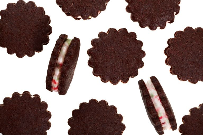 A cascade of Chocolate-peppermint sandwich cookies on a white background.