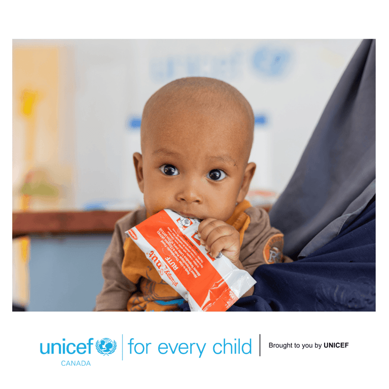 Small bald toddler chewing on the wrapper of ready-to-use therapeutic food that treats malnutrition.