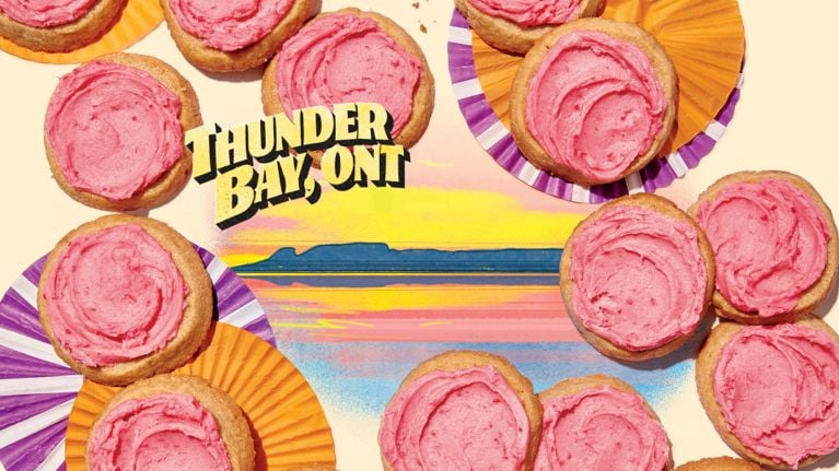 A display of sugar cookies with pink frosting are arranged over an illustration of a Thunder Bay landscape in a story about Christmas cookies styled after Canadian desserts.