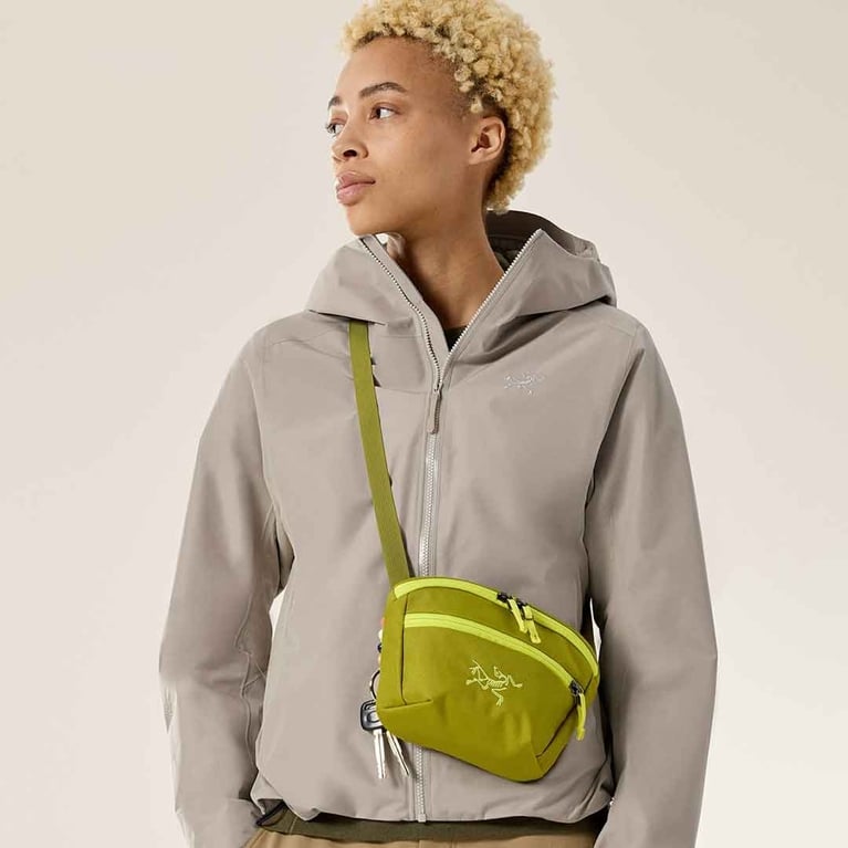 An model wearing an arc'teryx mantis pouch in green and yellow (or olive moss and euphoria) for a post on the best under $50 gifts in canada
