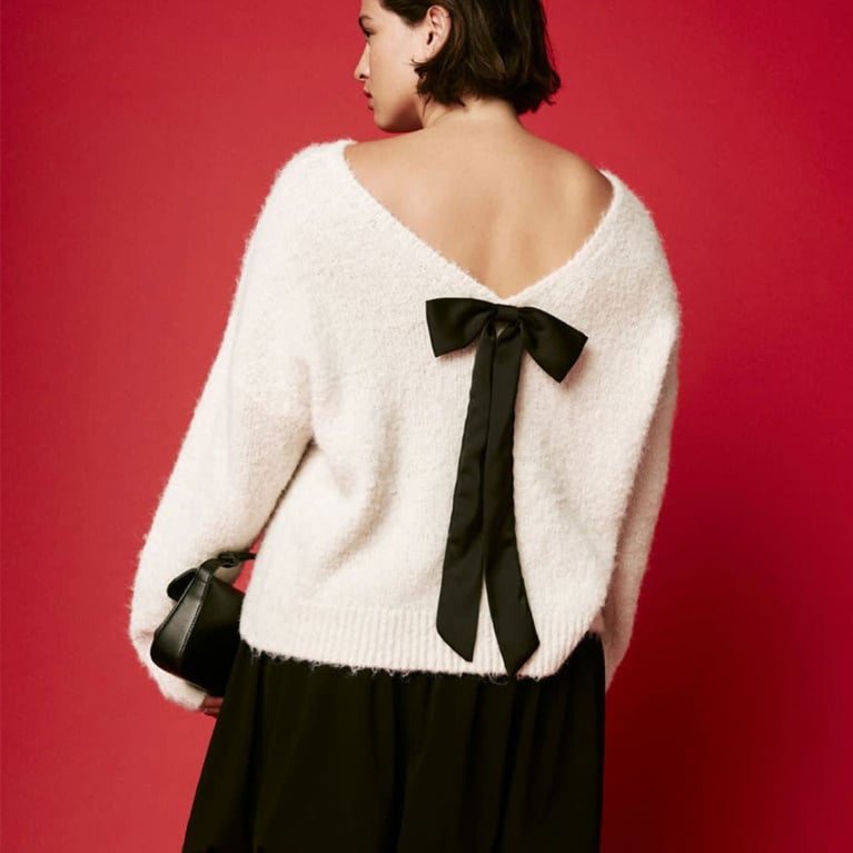 A woman in a cream sweater with a black bow on the back from reitmans in a post about best black friday deals canada.