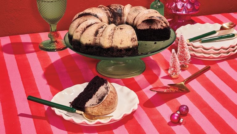 A chocoflan on a green platter on a pink-and-red striped tablecloth as part of a Feliz Navidad menu.