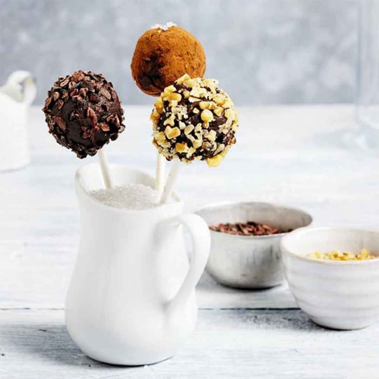 Three eggnog triffles on sticks, standing up in a pitcher filled with sugar.