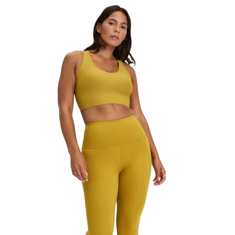 A woman wearing a matching mustard yellow fitness set from Knix in a post about best fitness gifts.