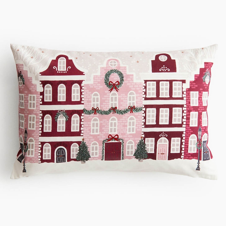A holiday cushion cover in tones of pink, green and red for an article about the best H&M Home holiday decor pieces for 2025.