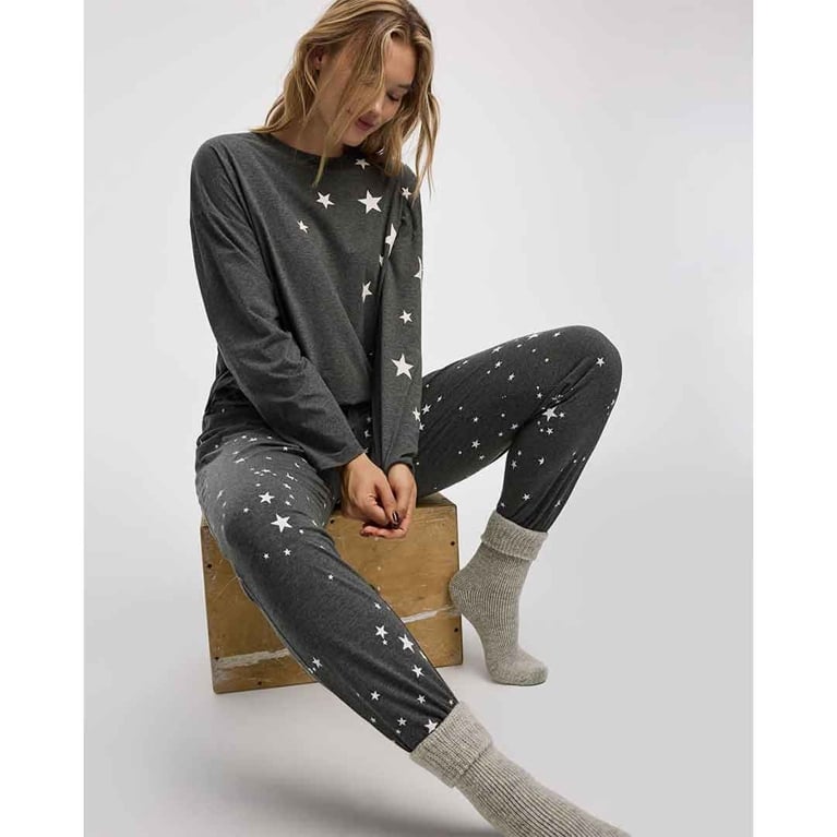 A pair of reitmans star pyjamas on a model sitting on a box for a piece on the best under-$50 christmas gifts