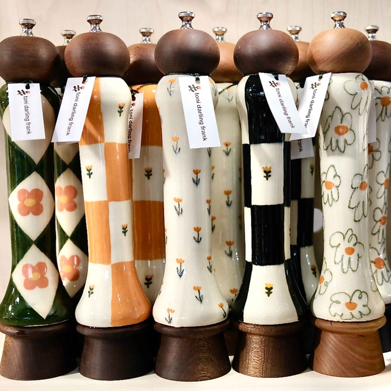 A collection of porcelain pepper grinders with wooden tops.