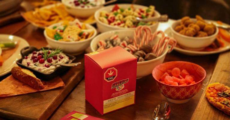 A table with mutiple bowls of snacks and a box of cannabis product