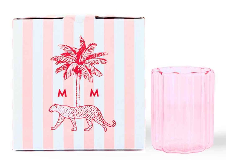 A pink fluted glass next to a pink striped box.