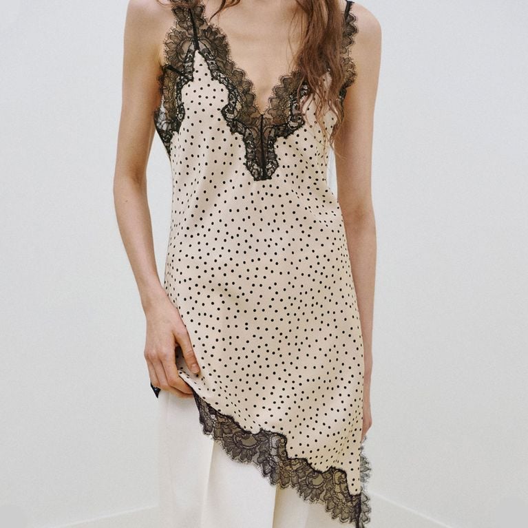 A model wearing a white and black polka dot top trimmed with lace from Mango to illustrate the polka dot trend.