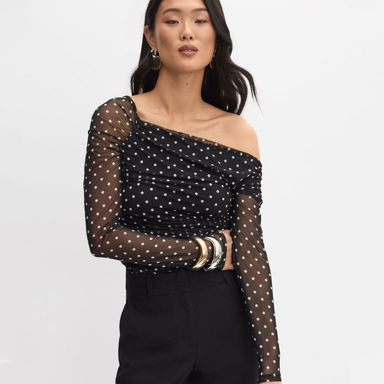 A model wearing a black and white polka dot mesh top from Melanie Lyne to illustrate the polka dot trend.