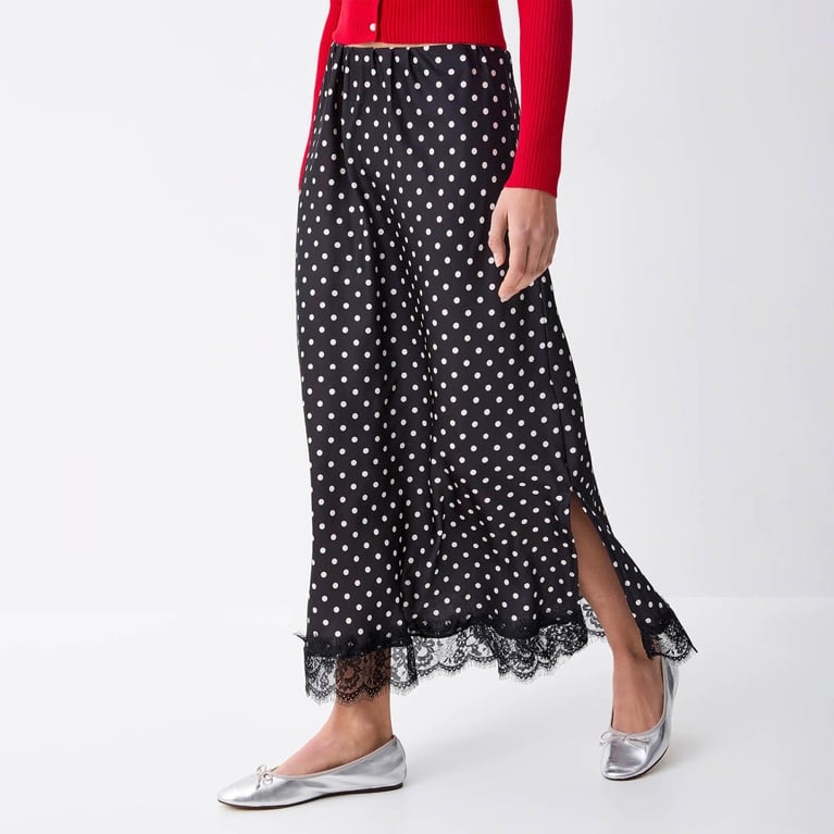 A model wearing a navy and white Twik polka dot skirt trimmed with lace from Simons to illustrate the polka dot trend.