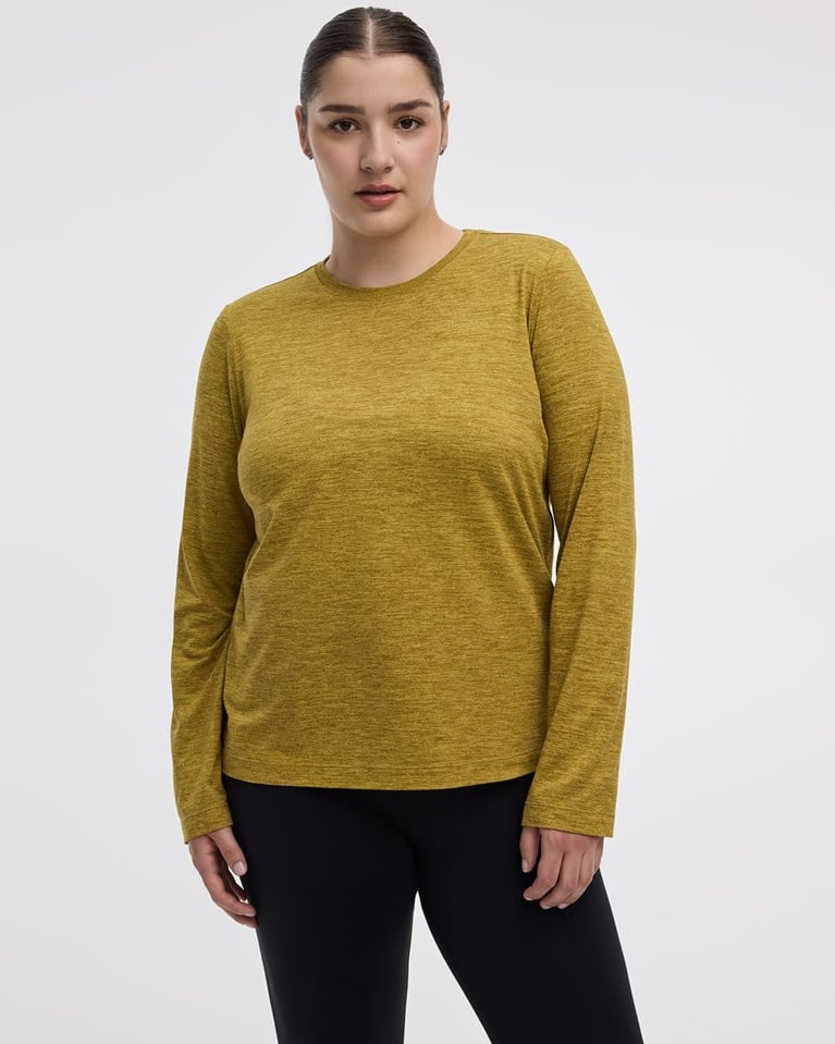 A photo of a woman in a golden yellow technical long-sleeve shirt used in a post on winter walking.