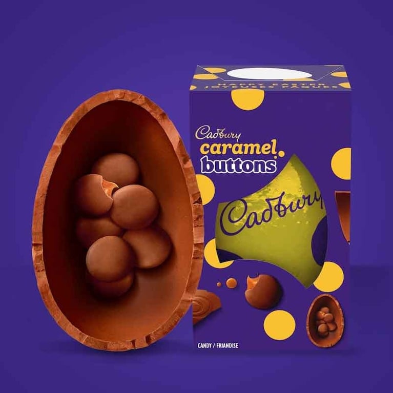 A Cadbury Caramel Buttons Easter egg set against a solid purple background. On the left, a large, thick milk chocolate egg shell is split open to reveal several round chocolate buttons filled with oozing caramel. On the right, the rectangular purple box features yellow polka dots and the "Cadbury Caramel Buttons" logo.
