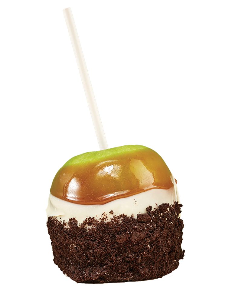 A green Granny Smith apple on a white stick, layered with glossy caramel, a thick band of white chocolate, and a heavy coating of dark chocolate cookie crumbles on the bottom half.