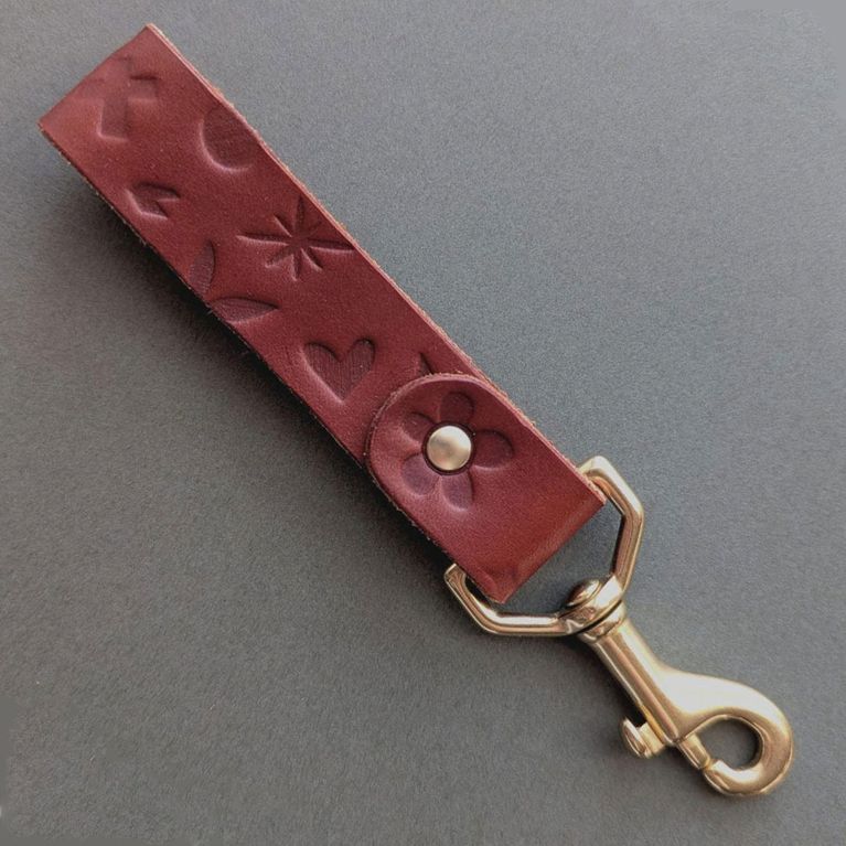 A leather lanyard embossed with flower designs from Light + Paper and Fitzy Design for an article about Etsy breakup registry gifts.