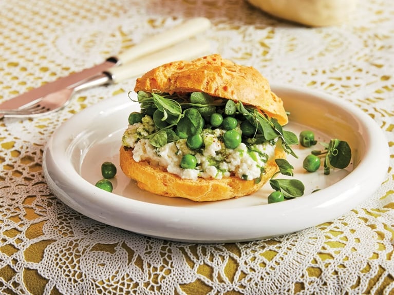 A cheese puff split in half and stuffed with ricotta cheese and peas.