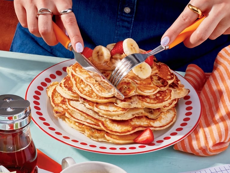 A stack of high protein banana pancakes on a red and white plate.
