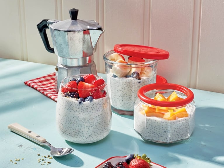 Three glass jars filled with overnight chia pudding and topped with berries.