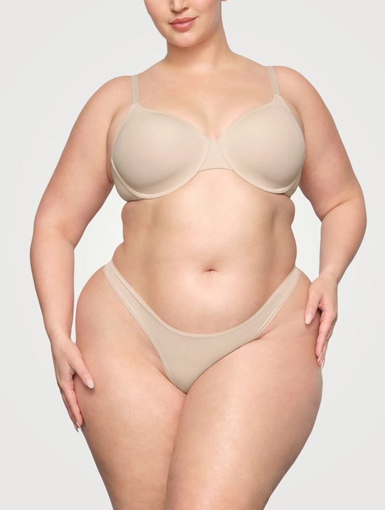 A model wearing a beige Skims Fits Everybody T-Shirt Bra for an article about comfortable bras for larger busts.
