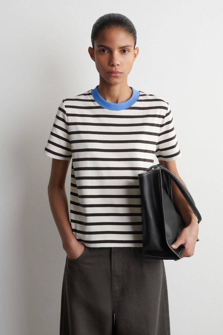 A woman standing in a striped t-shirtfor a post on COS Canada online.