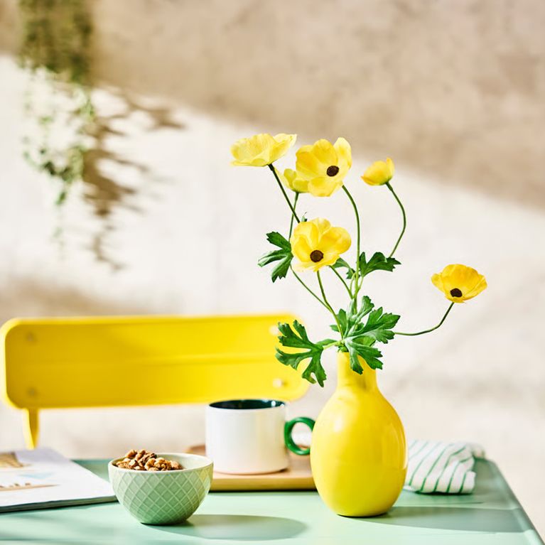 A faux flower in a yellow vase from IKEA's Easter Collection.