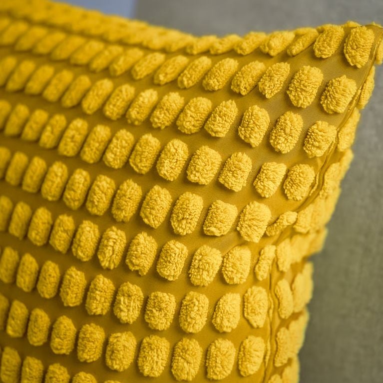 A yellow textured SVARTPOPPEL pillow cover from IKEA's Easter collection.
