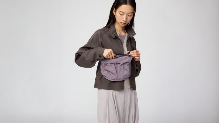 A model wearing a purple Uniqlo U Packable Cross-Body Bag.