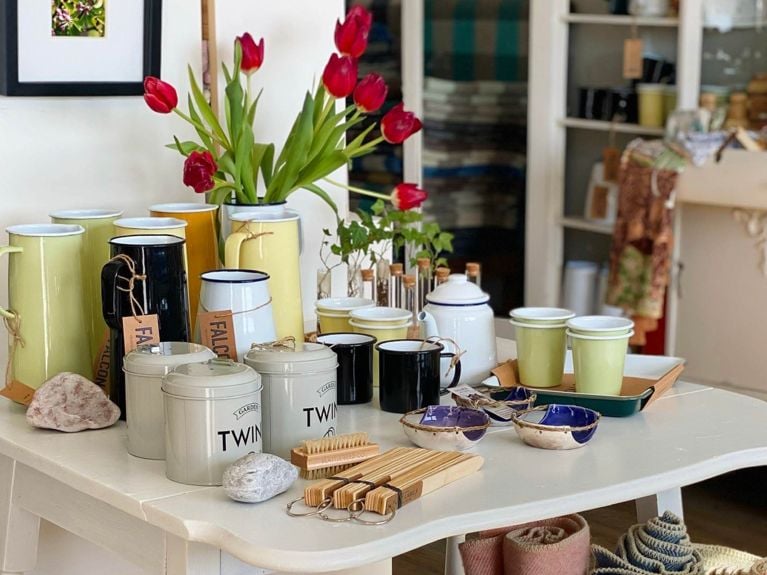 A shop table at Croft Shop with a groupin of enamelware, including a pitcher filled with red tulips, used in a post on what to do in Prince Edward Island.