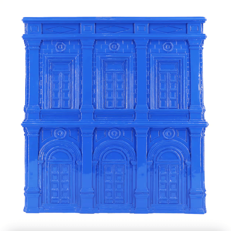 An indigo side table with a house motif on it from the Michaels Jonathan Adler collection.