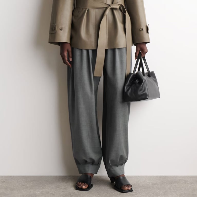 A model wearing COS Pleated Wool-Blend Balloon-Leg Pants for an article about the balloon-hem pants trends.