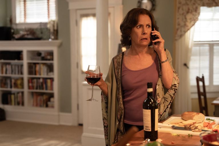 A photo of a woman holding a glass of red wine while on the phone used in a post about dan levy big mistakes
