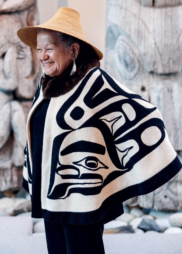 A photo of an older woman in a white shawl with black Haida artwork on it used in a post about Dorothy Grant CAFA Awards.