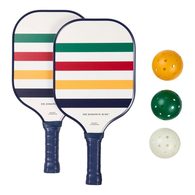A Hudson's Bay Canadian Tire Summer Collection '26 Pickelball Set with green, red, yellow and navy blue stripes on the paddles and 3 wiffle balls (in yellow, green and white) for an article about the new collection