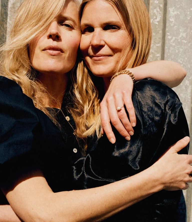 A photo of two women in black with their arms wrapped around each other in a post about horses atelier closed.