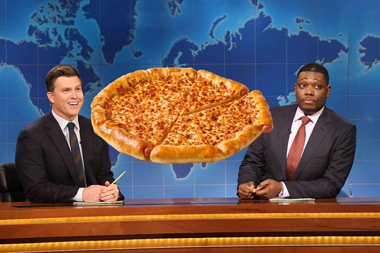 A photo of a hot dog pizza in between two men in suits at a news desk used in a post on hot dog pizza saturday night live.
