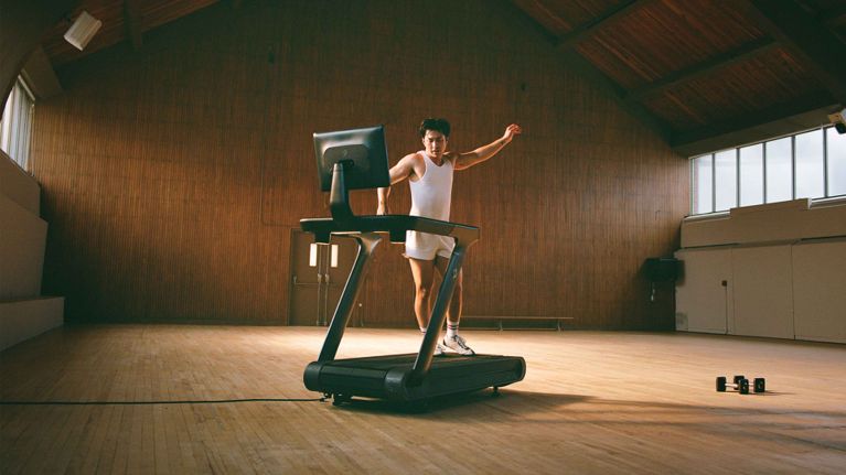 A man in a white tank top dancing on a treadmill in a post about hudson williams peloton.