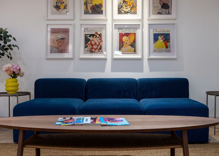 A blue couch and frames of archival Chatelaine covers, on the set for Chatelaine's podcast Group Chat, furnished by IKEA Canada.