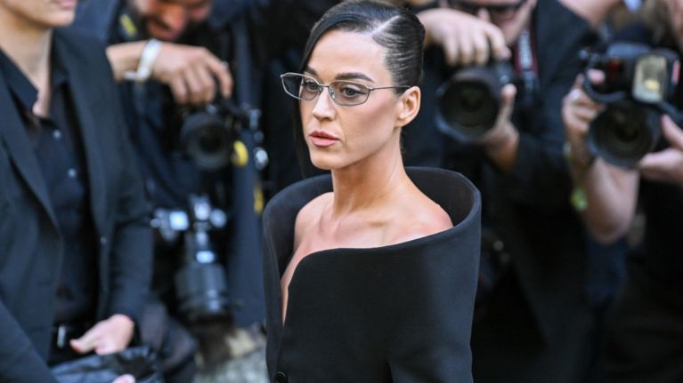 A photo of Katy Perry wearing glasses and a black coat.