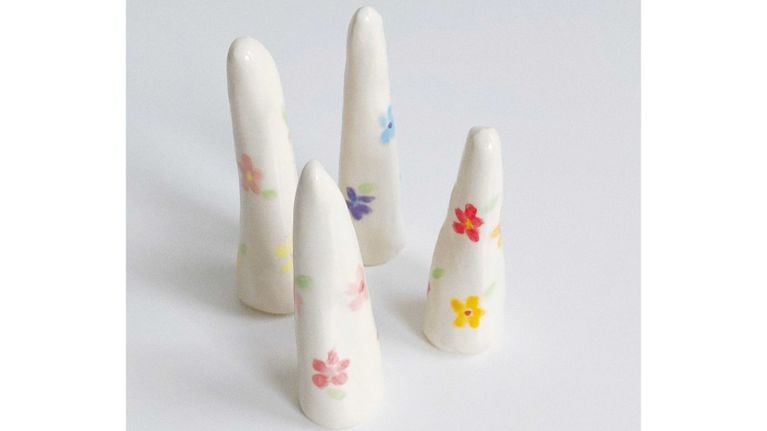 Four ceramic ring holders with flowers painted on them, used in a post about best organizing tips.