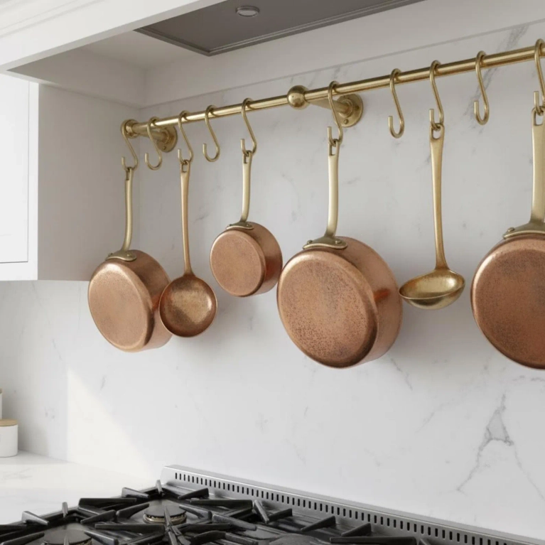A brass hanging pot rack with copper pots hanging on it.