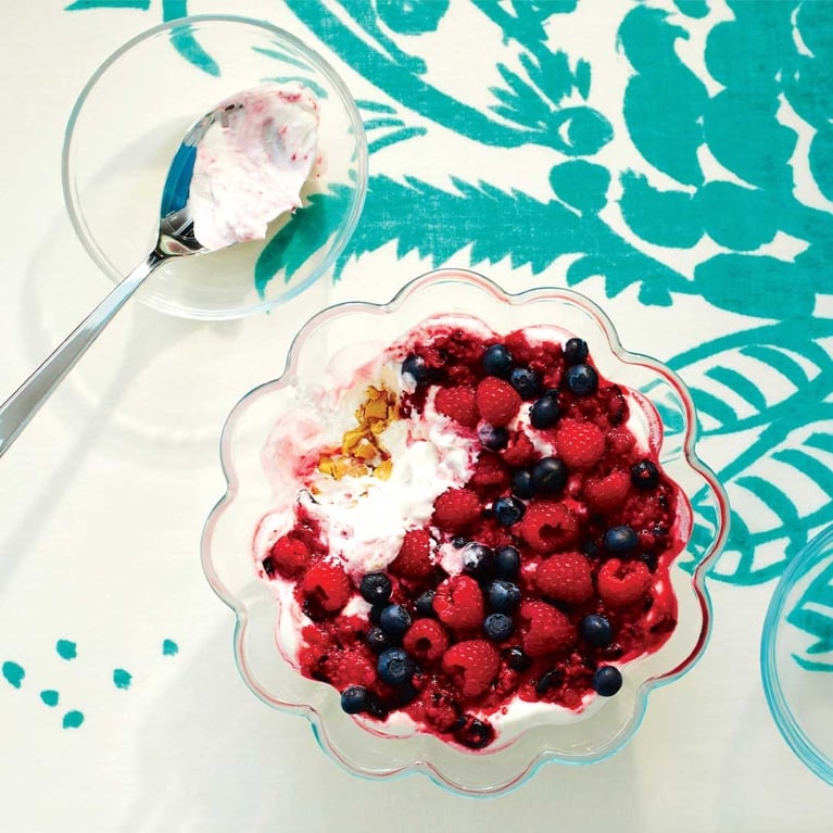 A bowl of ginger berry cookies and cream trifle on a white and blue turquoise tablecloth.
