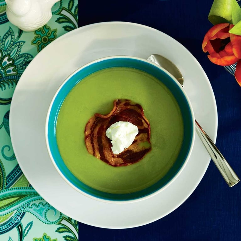 A bowl of green pea and white bean soup topped with fried pancetta and goat cheese.