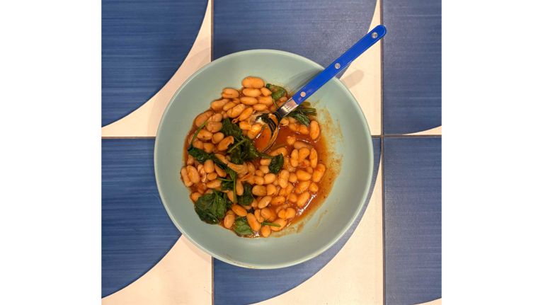 A sage green bowl filled with harissa baked beans.