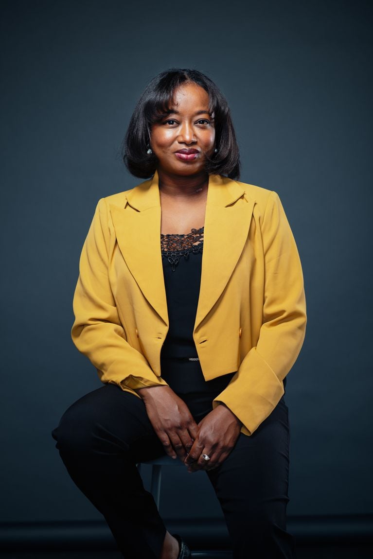 A portrait of a woman in a yellow blazer and black pants.